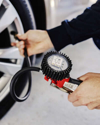 Hands checking on tire pressure, car service. Mechanic's hands checking on tire pressure in mechanic's shop on car service.